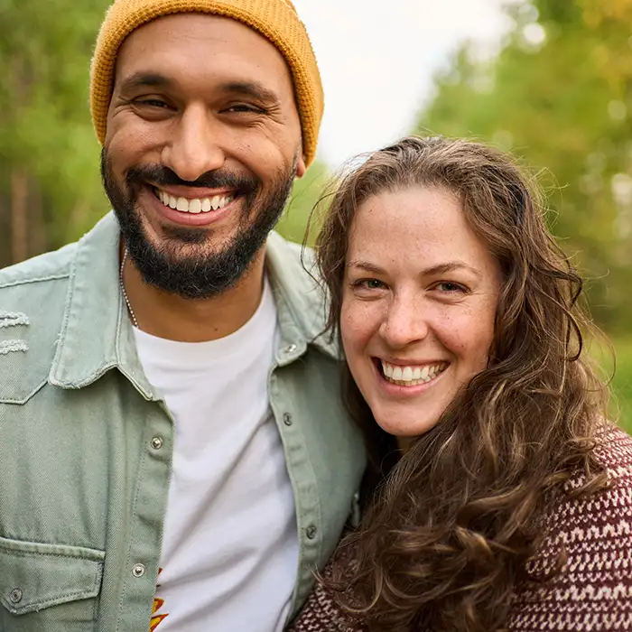 man and woman smiling together outdoors near trees